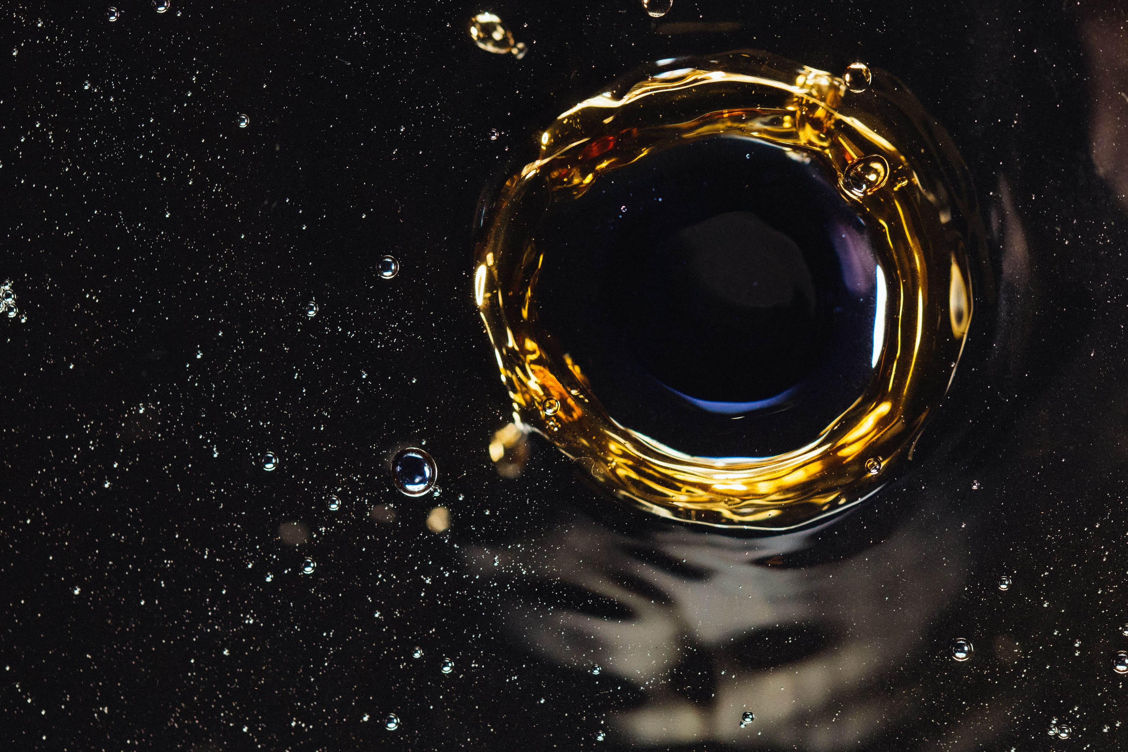 A ring of golden oil swirling on a dark liquid surface