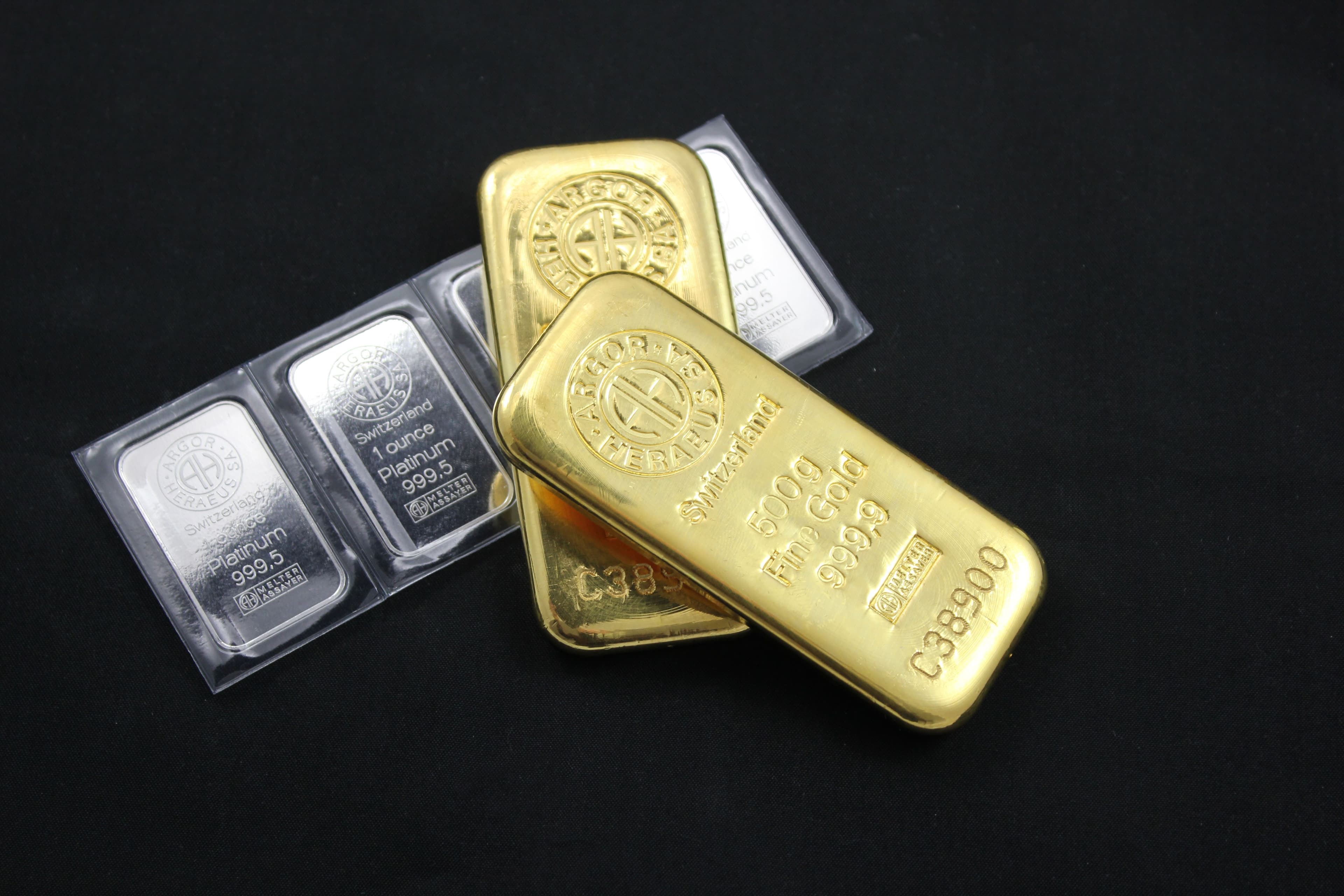 Gold and platinum bars stacked on a dark surface
