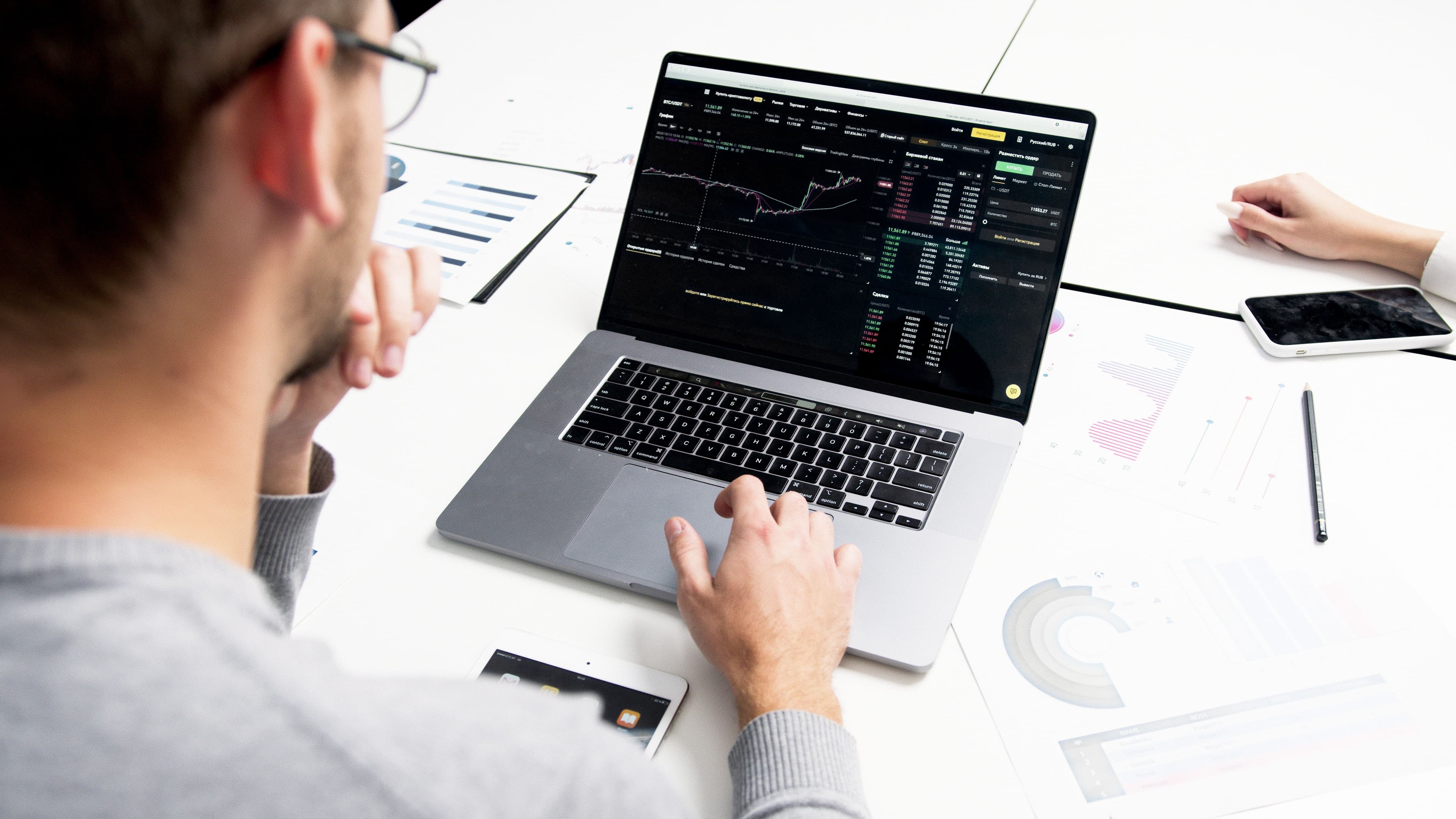 A person analyzing stock market charts and investment data on a laptop at a desk